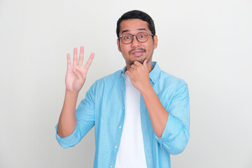 Wall Mural - Adult Asian man showing curious face expression while giving four fingers sign