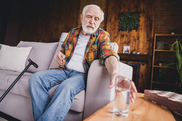 Sticker - Photo of lonely upset retired man dressed plaid shirt sitting couch drinking water pills indoors apartment