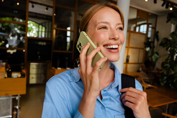 Wall Mural - Young white woman wearing shirt smiling while talking on cellphone