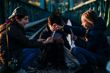 Group Of Three Children Playing Cards In A Train Track