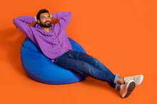 Full Length Portrait Of Positive Nice Person Sit Comfy Bag Hands Behind Head Take Nap Isolated On Orange Color Background