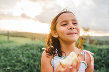 Hispanic Girl Eating Apple In Countryside