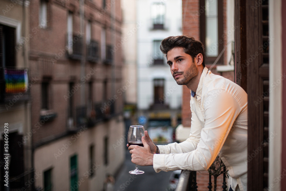 Focused young man with wine glass on balcony Stock Photo | Adobe Stock