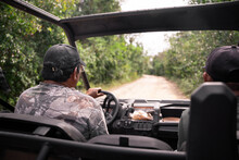Driver In Camouflage Driving UTV On Road Past Forest