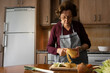 © ADDICTIVE STOCK - Senior woman peeling potatoes while cooking in kitchen