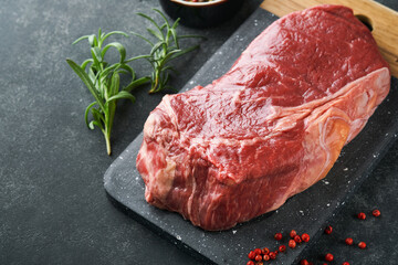 Steaks. Fresh New York Steaks raw with spices rosemary and pepper on black marble board on gray background. Top view. Mock up.