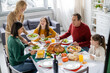 © LIGHTFIELD STUDIOS - Cheerful teenager sitting near multiethnic family and tasty thanksgiving dinner at home
