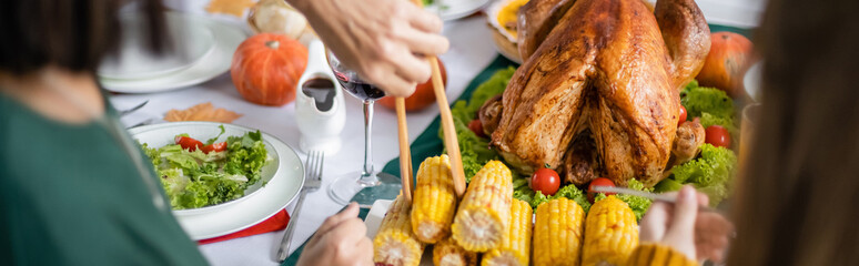 Wall Mural - Cropped view of woman taking corn near grandchild and thanksgiving turkey at home, banner