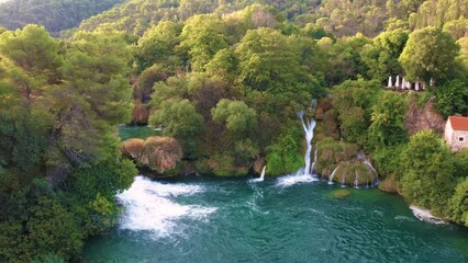 Wall Mural - Krka, Croatia - 4K Flying backwards over the beautiful Krka Waterfalls in Krka National Park on a bright summer morning with green foliage and turquoise water