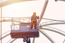 Construction Worker Work At High Construction Roof On Crane Platform Lift With Safety Equipment