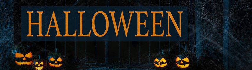 Wall Mural - Scary Halloween celebration holiday party card banner panorama - Many spooky carved glowing pumpkins with cemetery fence, Jack O’Lantern in the dark night