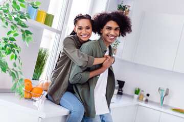 Poster - Photo of charming cheerful couple spend time together in kitchen room girlfriend hug her boyfriend behind feel comfy