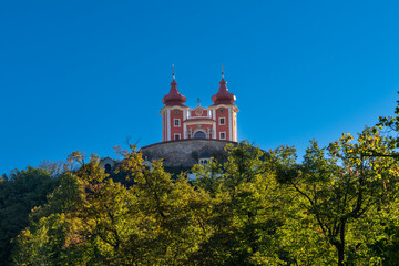 Poster - view of the red Calvary Banska Stiavnica under a blue sky with forest in foreground