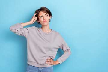 Photo of minded lady stylish outfit sweatshirt look empty space arm touch hairdo hmm doubt solution isolated on blue color background