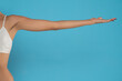 © vladimirfloyd - Young woman's stretched skinny arm and open palm holding imaginary product. Isolated on blue background.