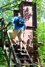 A Male Tourist Climbs A Bridge Over A Mountain River While Hiking