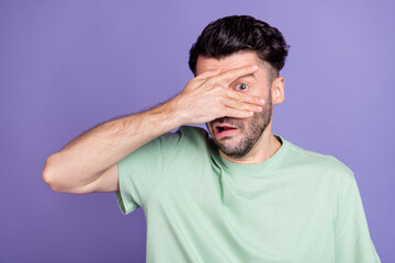 Poster - Portrait of scared stressed terrified man with brunet hairdo dressed t-shirt hiding hand cover eye isolated on purple color background