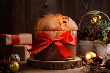 Traditional Italian Christmas Cake Panettone with red bow and festive decoration on wooden rustic background. Homemade artisan sourdough panettone is classic italian Christmas Food and Edible gift