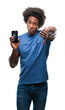 © Krakenimages.com - Afro american man holding broken smartphone over isolated background with angry face, negative sign showing dislike with thumbs down, rejection concept