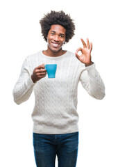 Poster - Afro american man drinking cup of coffee over isolated background doing ok sign with fingers, excellent symbol