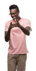 Sticker - Young african american man wearing pink t-shirt pointing fingers to camera with happy and funny face. Good energy and vibes.