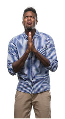 Canvas Print - Young african american man wearing blue shirt begging and praying with hands together with hope expression on face very emotional and worried. Asking for forgiveness. Religion concept.