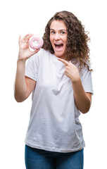 Wall Mural - Young brunette girl eating donut over isolated background very happy pointing with hand and finger