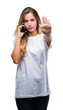 © Krakenimages.com - Young beautiful blonde woman calling using smartphone over isolated background with open hand doing stop sign with serious and confident expression, defense gesture