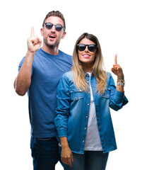 Poster - Young couple in love wearing sunglasses over isolated background pointing finger up with successful idea. Exited and happy. Number one.