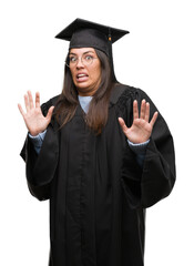 Poster - Young hispanic woman wearing graduated cap and uniform afraid and terrified with fear expression stop gesture with hands, shouting in shock. Panic concept.