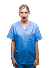 Canvas Print - Young beautiful blonde doctor surgeon nurse woman over isolated background afraid and shocked with surprise expression, fear and excited face.