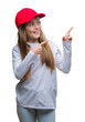 © Krakenimages.com - Young beautiful girl wearing red cap isolated background smiling and looking at the camera pointing with two hands and fingers to the side.