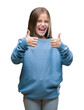 Young beautiful girl wearing winter sweater over isolated background success sign doing positive gesture with hand, thumbs up smiling and happy. Looking at the camera with cheerful expression