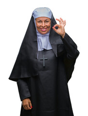 Poster - Middle age senior christian catholic nun woman over isolated background smiling positive doing ok sign with hand and fingers. Successful expression.