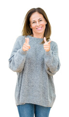 Beautiful middle age woman wearing winter sweater over isolated background pointing fingers to camera with happy and funny face. Good energy and vibes.