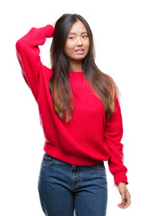 Wall Mural - Young asian woman wearing winter sweater over isolated background confuse and wonder about question. Uncertain with doubt, thinking with hand on head. Pensive concept.