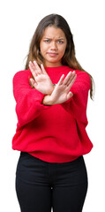 Canvas Print - Young beautiful brunette woman wearing red winter sweater over isolated background Rejection expression crossing arms and palms doing negative sign, angry face