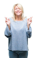 Sticker - Young beautiful blonde woman wearing winter sweater over isolated background smiling crossing fingers with hope and eyes closed. Luck and superstitious concept.