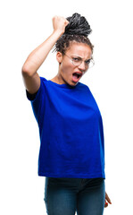 Canvas Print - Young braided hair african american girl wearing glasses over isolated background angry and mad raising fist frustrated and furious while shouting with anger. Rage and aggressive concept.