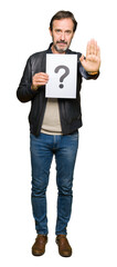 Poster - Handsome middle age man holding paper with question mark with open hand doing stop sign with serious and confident expression, defense gesture