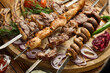 Shashlik from different meats on barbecue skewers with vegetables and lavash on wooden board. Top view. Food background.
