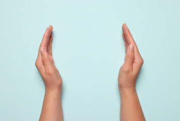 Wall Mural - woman holding on light blue background, closeup of hands. space for text