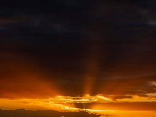 Wall Mural - Dramatic sunset sky with sun rays and warm orange colors.