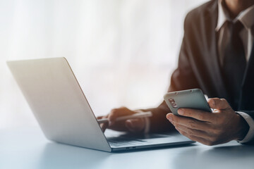 Business man looking at financial information from a mobile phone, he is checking company financial documents, he is an executive of a startup company. Concept of financial management.