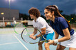 © NDABCREATIVITY - Tennis sport people concept. Mixed doubles player hitting tennis ball with partner standing near net