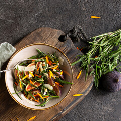 Wall Mural - bowl with salad with figs, parmesan cheese and arugula on the table