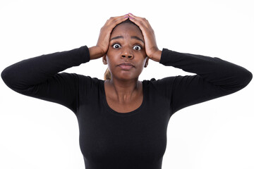 Wall Mural - Portrait of terrified African American woman. Scared young model in black shirt with ponytail looking at camera with hands on head. Shock, fear concept.