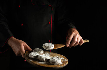 Meat cutlets with veal sprinkled with flour on a cutting board in the hands of the chef. Free space for advertising on a black background