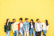 © Davide Angelini - Diverse community of young people smiling together on a yellow wall background - Multiracial college students having fun laughing outside - Youth culture concept