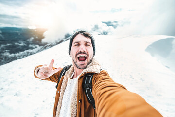 Wall Mural - Handsome man taking selfie on winter snow mountain 